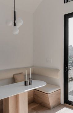 a room with a table, bench and glass door that leads to a balcony overlooking the city