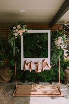 an outdoor wedding ceremony with greenery, flowers and the word mr and mrs spelled in copper letters