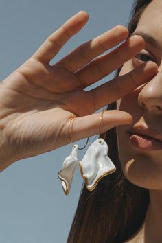 a close up of a person holding something in their hand with the sky behind them