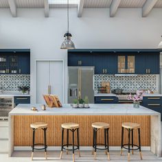 a kitchen with blue cabinets and stools in front of an island counter that has three bar stools on it