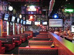 the inside of a sports bar with many televisions on the wall and people sitting at tables