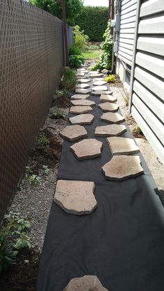 a walkway made out of stepping stones in front of a house with a black tarp covering it