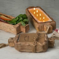 some candles are sitting in wooden containers on a table