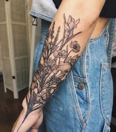 a woman's arm with flowers and leaves tattooed on the left side of her arm