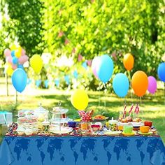 a blue table topped with lots of food next to balloons and trees in the background