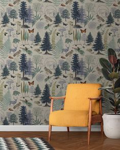 a yellow chair sitting in front of a wallpaper with trees and birds on it