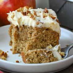 a piece of carrot cake with white frosting and pecans is on a plate