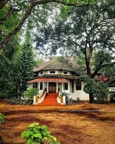 a white house surrounded by trees and dirt