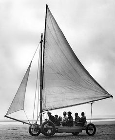 a group of people riding on the back of a small boat in the ocean with sails down