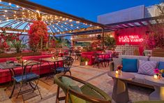 an outdoor patio with tables, chairs and couches covered in colorful lights at night