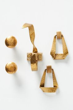 three pairs of gold earrings on a white surface with one earring in the middle