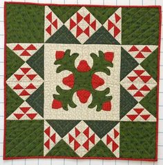 a green and red quilted square with an image of a frog in the center