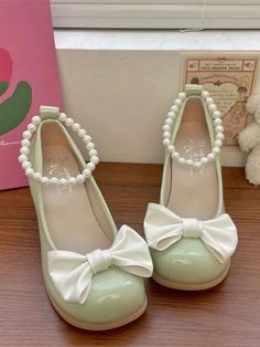 a pair of mint green shoes with white pearls and a bow on the front, sitting next to a pink box