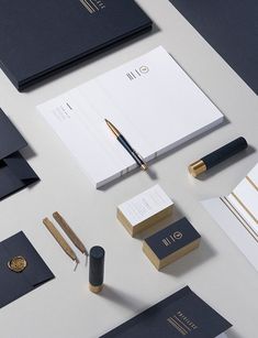 various stationery items displayed on white surface with gold trimmings and black paper