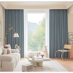 a living room filled with furniture and a large window covered in blue drapes