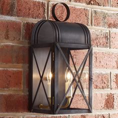 an old fashioned lantern on the side of a brick wall with a candle in it