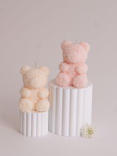 two small teddy bears sitting on top of each other in front of a white background