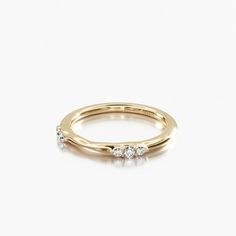 a yellow gold ring with three diamonds on the top and bottom, set against a white background