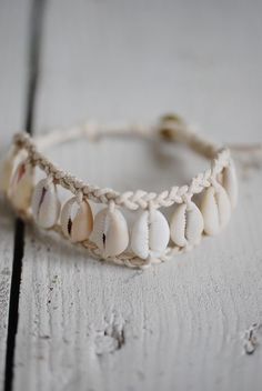 a close up of a bracelet on a wooden surface with shells attached to the bead