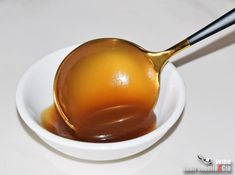 a spoon filled with liquid on top of a white bowl