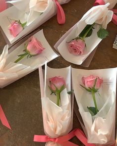 pink roses are wrapped in white paper and tied with ribbons