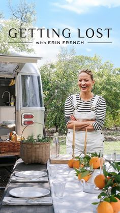 a woman standing in front of a table with oranges and an ice cream truck