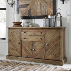 a wooden sideboard with metal accents in a white living room, next to a painting on the wall