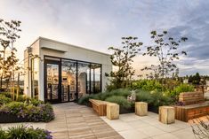 an outdoor area with benches and plants on the roof terrace at sunset or sunrise time