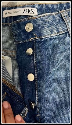 a person is holding their jeans open and showing the button on the back of his pants