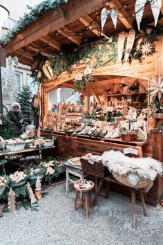 an outdoor christmas market with lots of holiday decorations and greenery on the outside wall