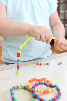 a child is playing with beads on the table