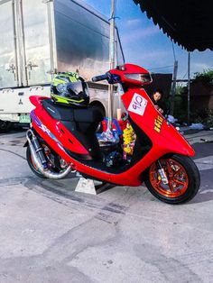 a red scooter parked in front of a trailer with two people sitting on it