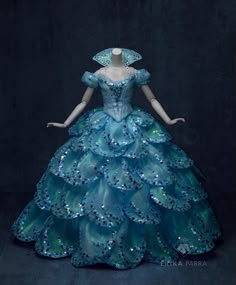 a blue dress with sequins on the skirt and headpiece is displayed in front of a black background