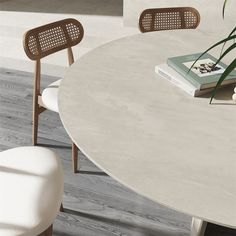 a white table with two chairs and a book on it next to a potted plant