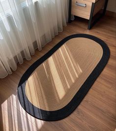 an oval rug on the floor next to a window