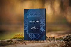 a blue book sitting on top of a wooden table next to trees and grass in the background