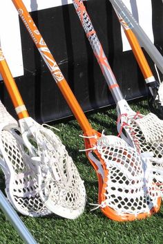 several lacrosse sticks and helmets are lined up on the grass