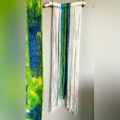 a wall hanging made out of yarn and bamboo sticks with two different colors on it