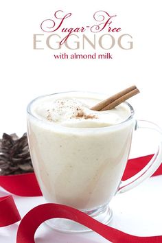 an eggnog drink in a glass mug with cinnamon stick and ribbon around it