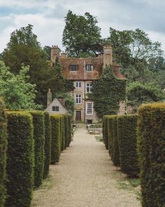 an old house surrounded by hedges and trees