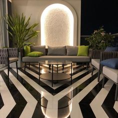 a living room with black and white flooring, couches and chairs in it