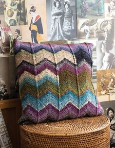 a pillow sitting on top of a wicker stool in front of a wall with pictures