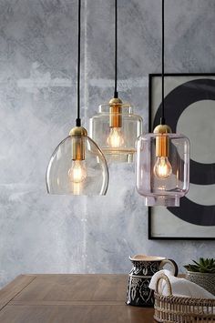 three glass pendant lights hanging over a wooden table