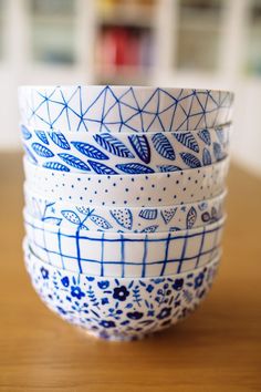 four blue and white bowls sitting on top of a wooden table next to each other