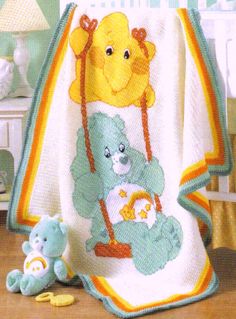 a crocheted baby blanket with teddy bears on it and a stuffed animal next to it