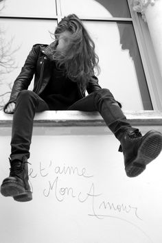 a woman sitting on top of a window sill with her feet up in the air