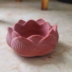 a pink flower shaped bowl sitting on top of a table