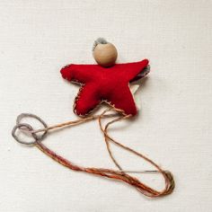 a red and white star shaped object with some string on it's side, sitting on a white surface