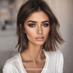 a woman with brown hair and makeup looks at the camera while posing for a photo