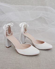 a pair of white high heels with pearls on the toe and heel straps are shown